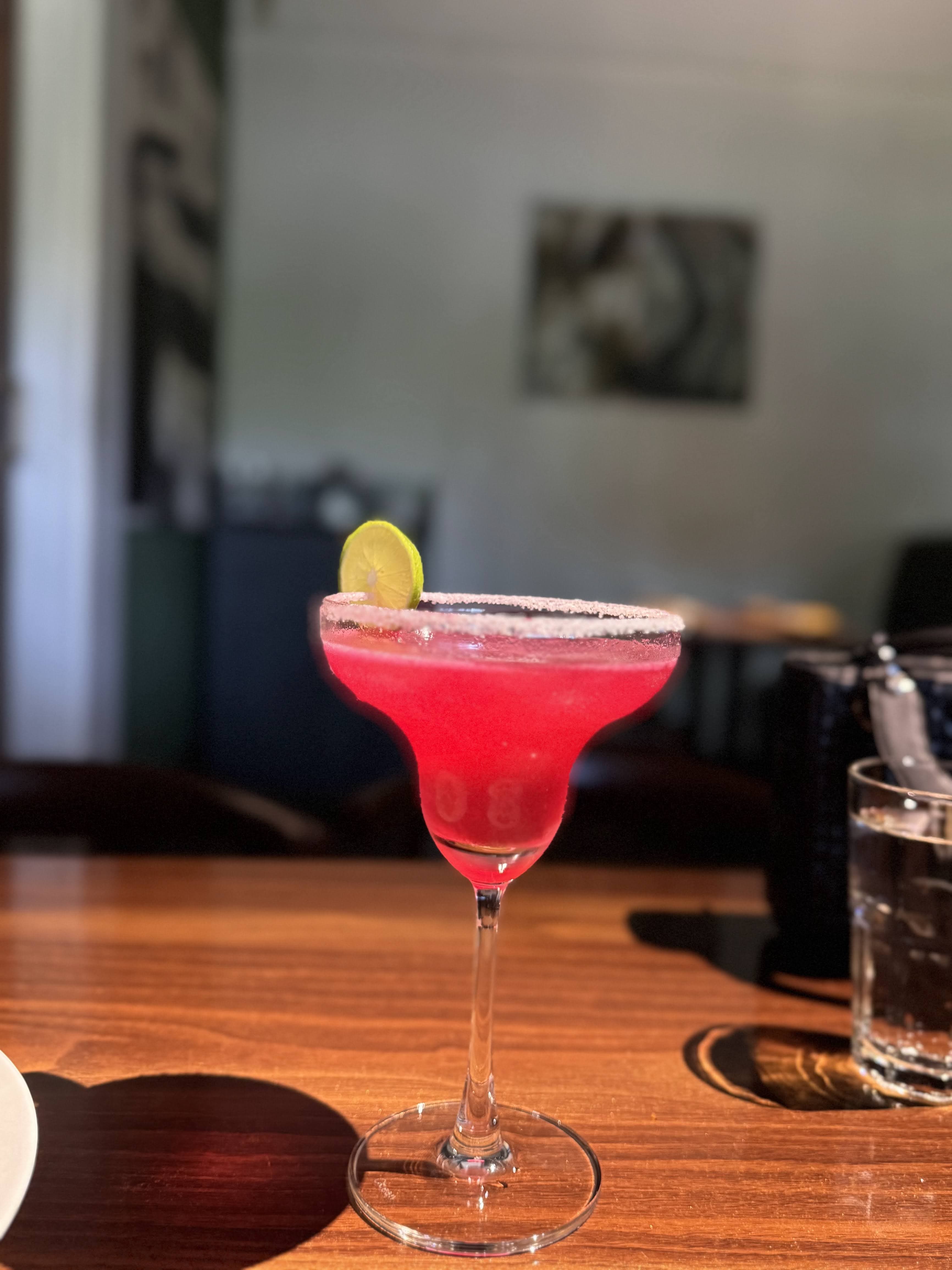 A pink margarita on a table in the afternoon light