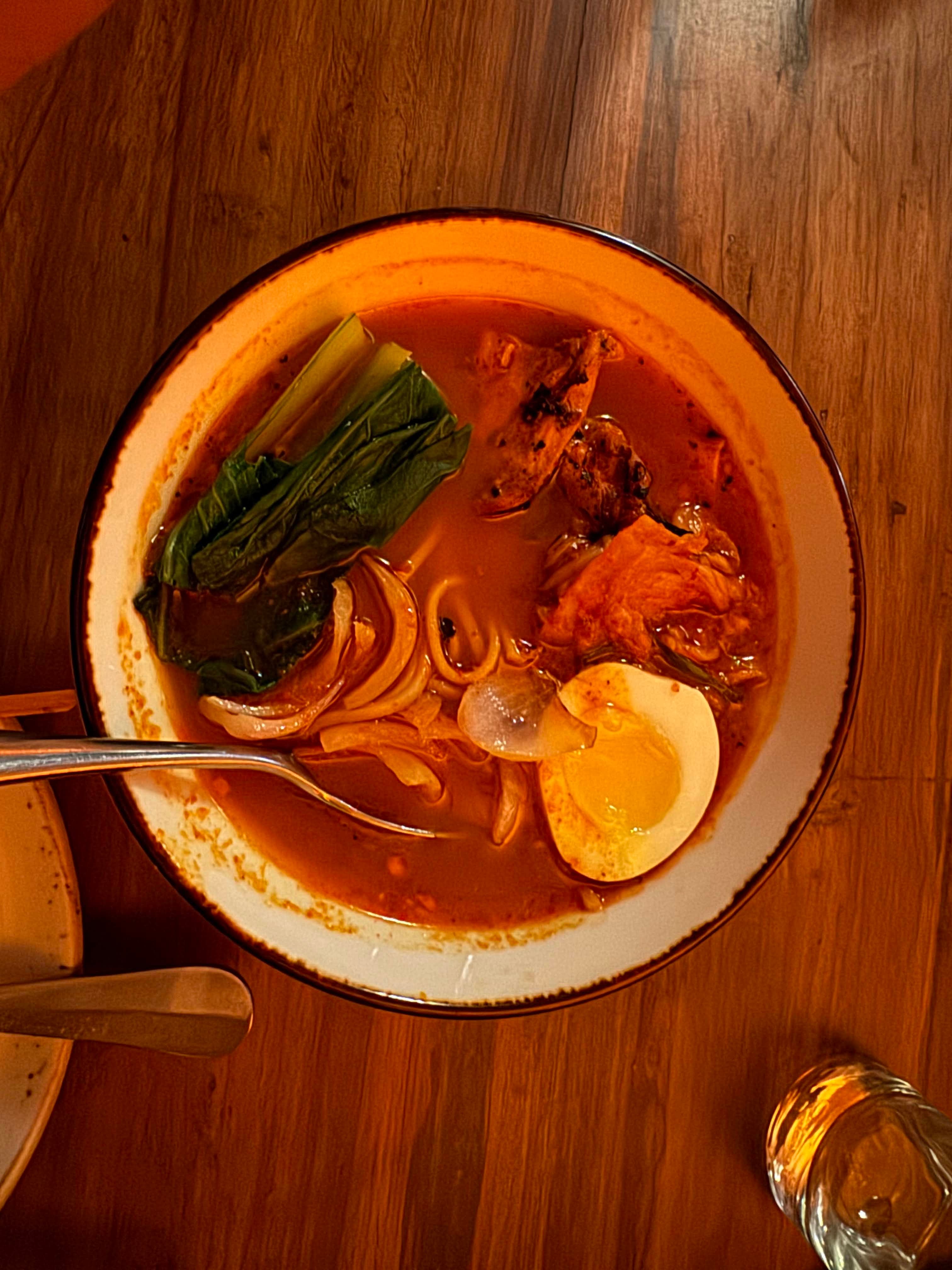 A bowl of spicy ramen on a wooden table